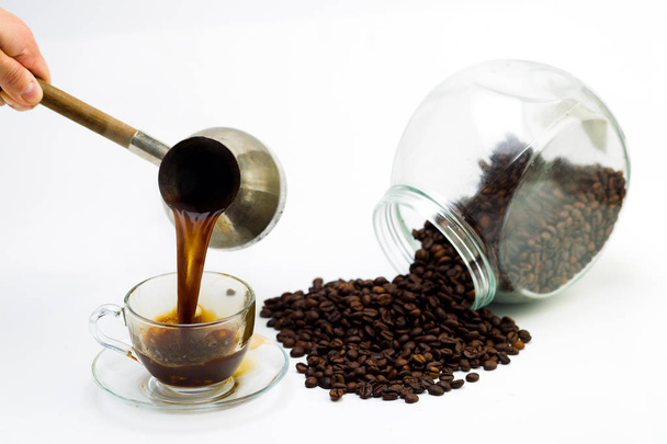 Black coffee in a glass cup and grains of coffee on a white back - Photo, image