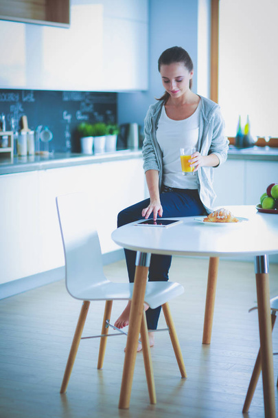 Mutfakta portakal suyu ve tableti olan genç bir kadın.. - Fotoğraf, Görsel