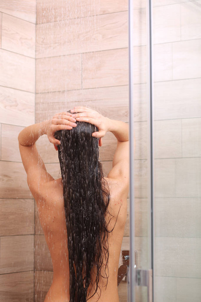 Young beautyful woman under shower in bathroom. - Fotó, kép