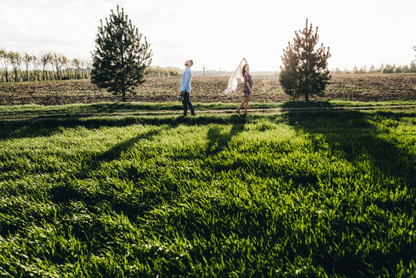 Young couple walking through the field - 写真・画像
