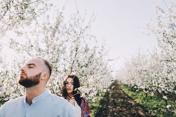 Young couple walking in the blooming garden - Фото, изображение