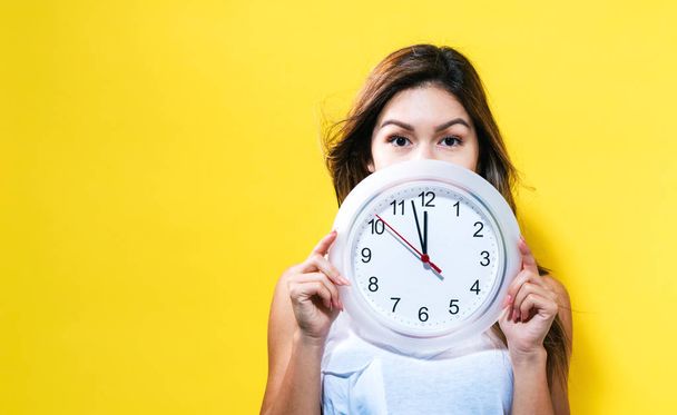 Woman holding clock showing nearly 12 - Foto, imagen