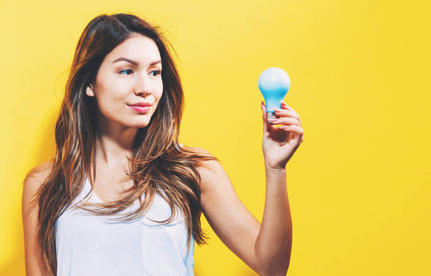 Young woman holding a light bulb - Foto, imagen