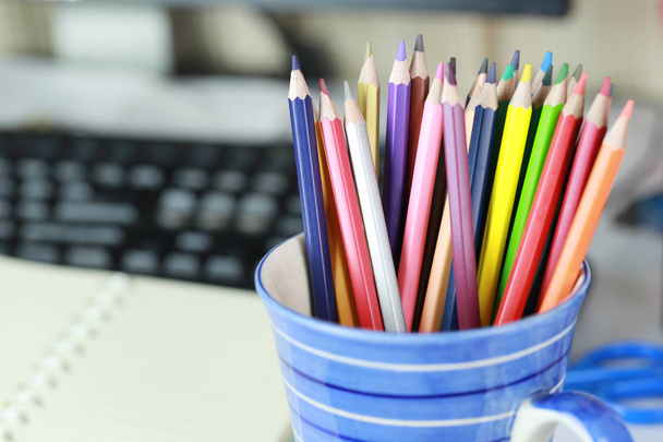 Crayon colorido na xícara azul na mesa de trabalho
. - Foto, Imagem