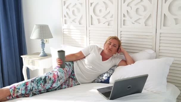 Woman laying on a bed using laptop 4 - Materiał filmowy, wideo