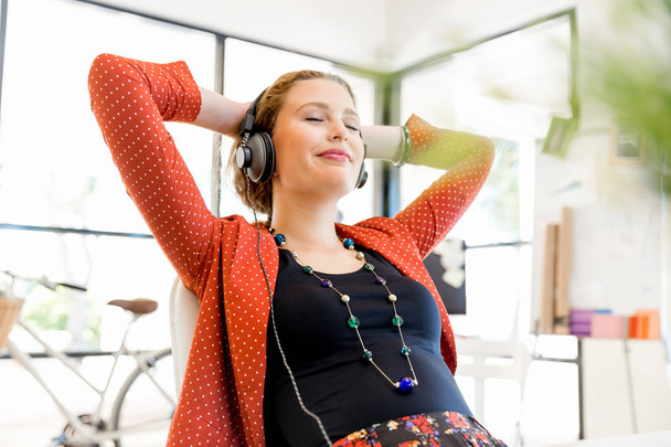 Young woman in office with headphones - Foto, Imagen