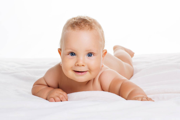 Cute smiling baby lying on towel isolated on white - Foto, Imagem