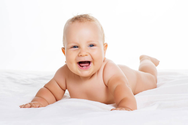 Cute smiling baby lying on towel isolated on white - Foto, afbeelding