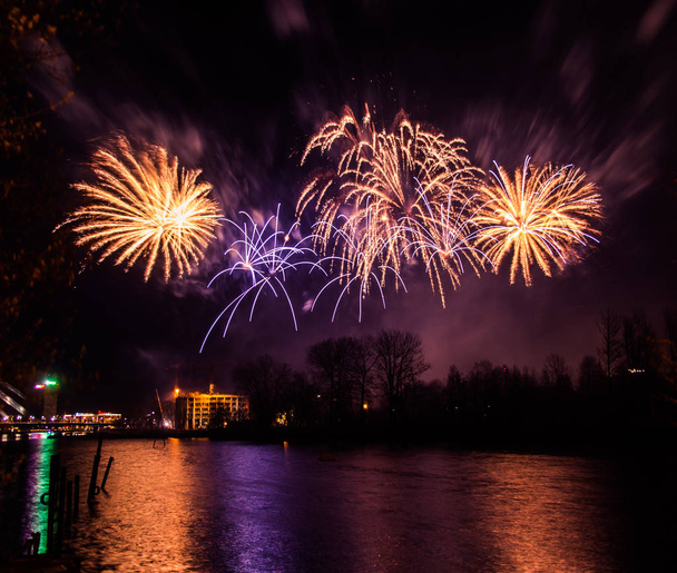 Abstract, blurry, bokeh-style colorful photo of fireworks above the river - Photo, Image