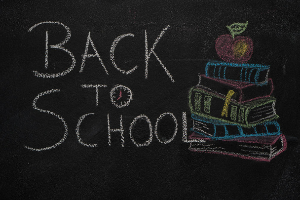 Вернуться к школьному тексту и стопке книг с яблоком, нарисованным на черной доске
 - Фото, изображение