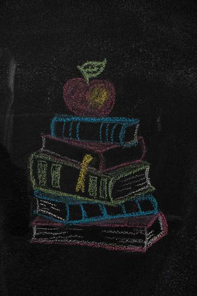 Bücherstapel mit Apfel auf schwarzer Tafel gezeichnet - Foto, Bild