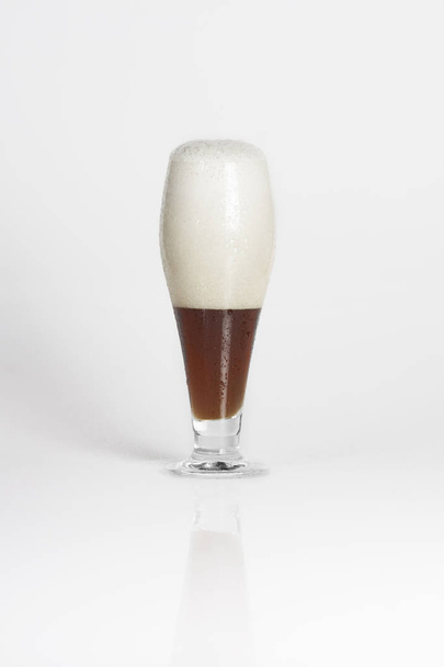 Mitad de vaso de cerveza fría oscura sobre un fondo blanco aislado
 - Foto, Imagen