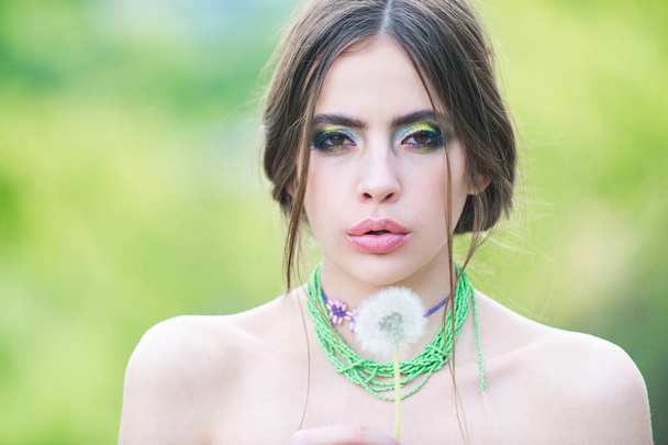 dandelion flower in hand of girl with fashionable makeup - Foto, afbeelding