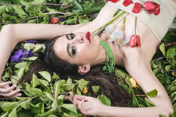 woman with fashionable makeup with flowers on green leaves - Photo, image