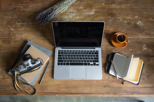 top view of laptop, diaries, vintage photo camera and cup of coffee on wooden tabletop - Photo, Image