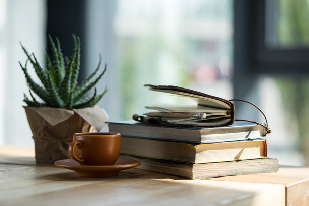 Datailní pohled knih, zápisník s tužkou a šálek kávy na dřevěný stůl  - Fotografie, Obrázek