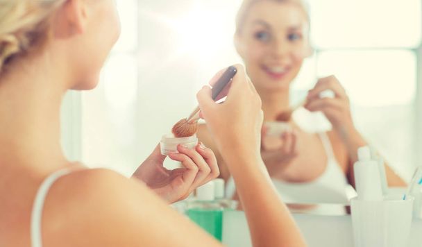 woman with makeup brush and powder at bathroom - Fotoğraf, Görsel