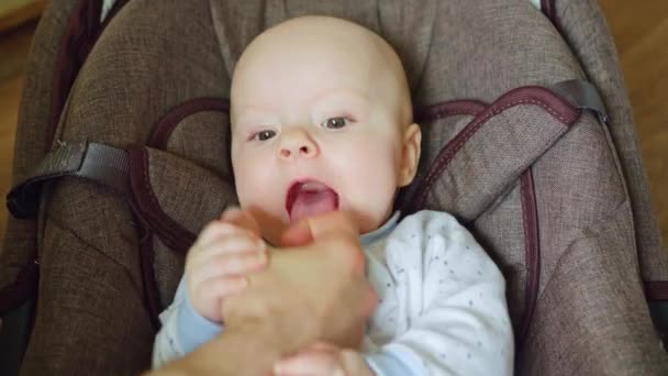 Μωρό ξαπλωμένη σε ένα καρότσι τρώει πατέρες δάχτυλο - Πλάνα, βίντεο