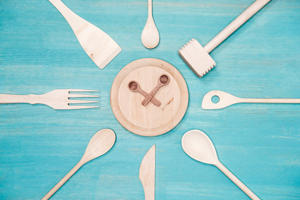 top view of various wooden kitchen utensils with clock symbol on plate - Foto, Imagem