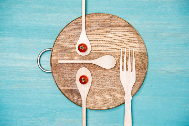 top view of wooden cooking utensils with tomatoes in form of face on kitchen board - Фото, зображення