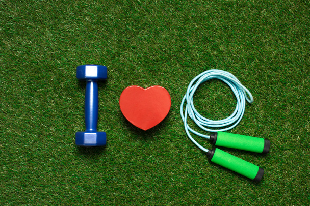 colorful dumbbell with heart symbol and skipping rope on the grass - Foto, Imagen