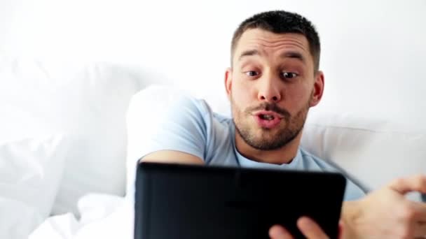 man with tablet pc drinking coffee in bed at home - Séquence, vidéo