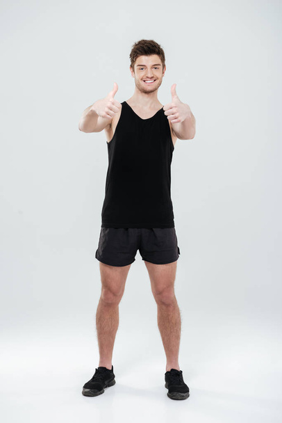 Happy young sportsman showing thumbs up gesture. - 写真・画像