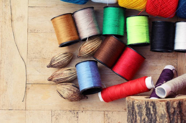 Kleurrijke draad voor het naaien op houten achtergrond - Foto, afbeelding