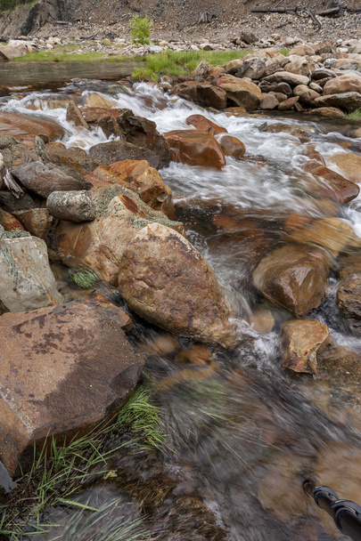 Вода тече над камінням і травою
. - Фото, зображення