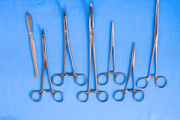 Instrumentos y herramientas quirúrgicas, incluidos bisturíes, pinzas y pinzas dispuestas en una mesa para una cirugía - Foto, imagen