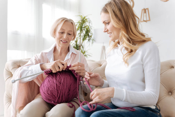 Young woman helping her mother with knitting - Foto, Bild