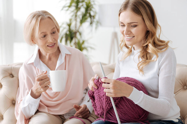 Senior mother watching her daughter knitting - Foto, afbeelding