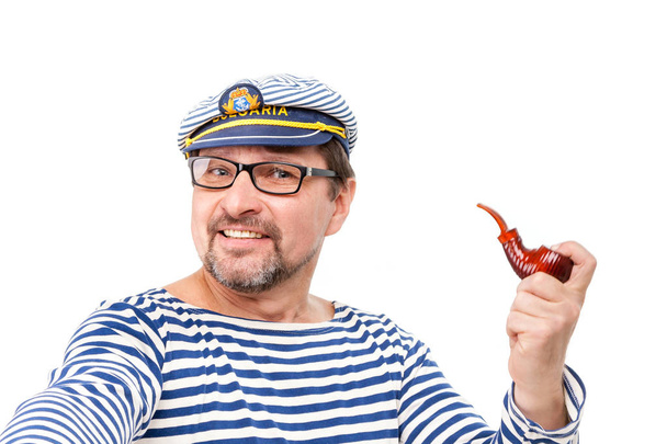 Un marin homme dans une casquette avec une pipe fumante devant une ba blanche
 - Photo, image