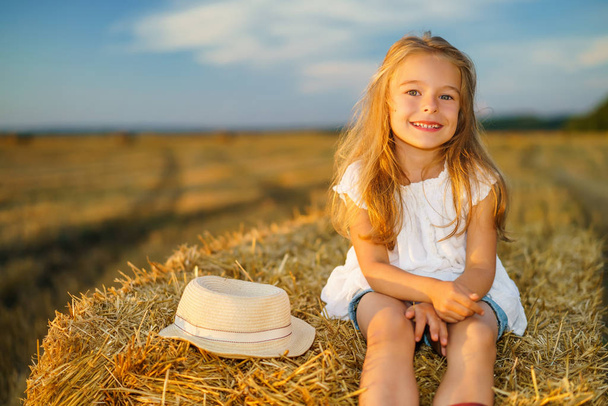 Little girl in a field with hay rolls - Фото, зображення