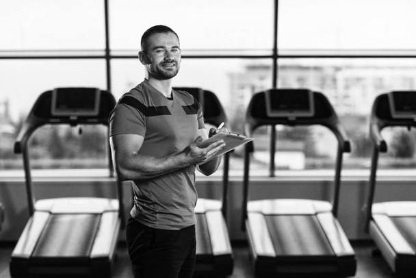 Personal Trainer Takes Notes On Clipboard In Gym - Foto, Imagen