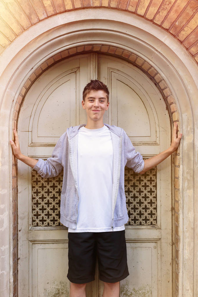portrét usměvavý mladý muž stojící před staré dveře - Fotografie, Obrázek