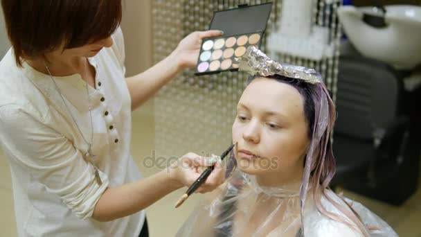 Hair stylist impose make-up, blonde with hair in blue paint. - Felvétel, videó