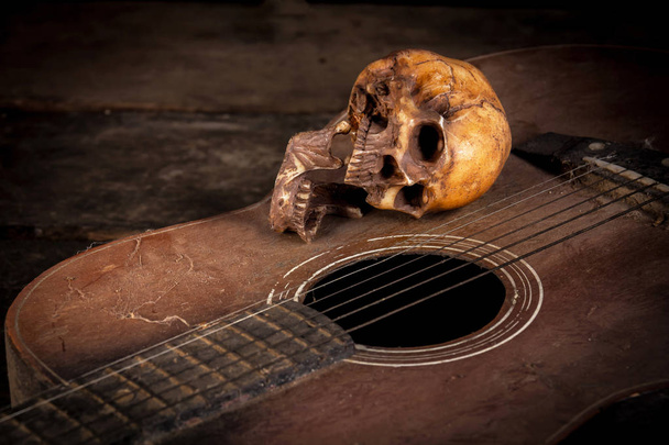 Νεκρή φύση με ανθρώπινο κρανίο σε φόντο κιθάρα - Φωτογραφία, εικόνα