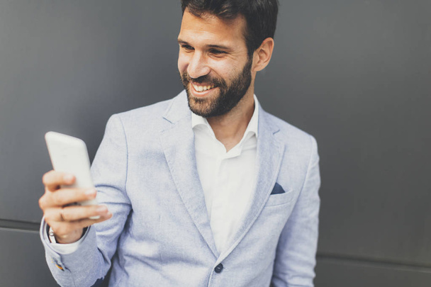 Retrato de un hombre de negocios pensativo sosteniendo teléfono inteligente al aire libre
 - Foto, imagen