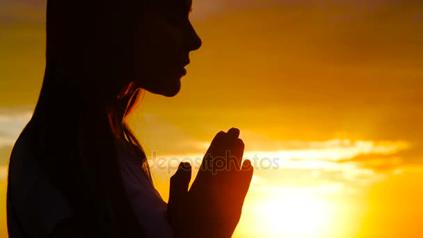 Silhouette of young woman praying at sunset - Footage, Video