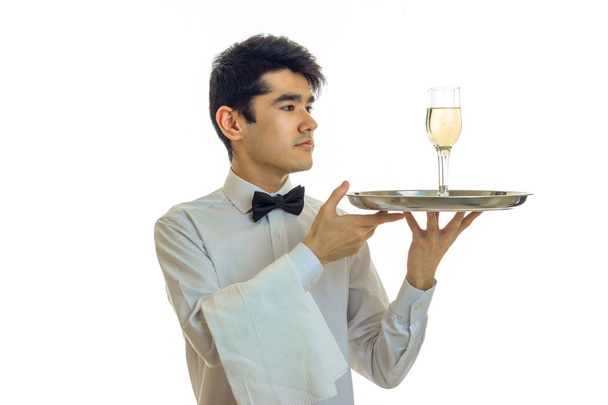stunning slender young waiter raised his hands in a tray with a glass of champagne - Photo, Image