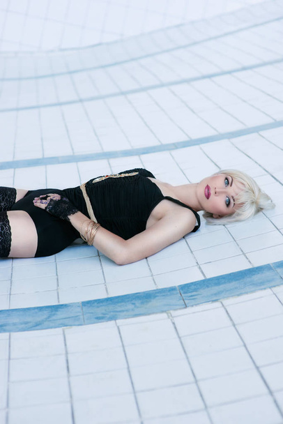 piękna młoda kobieta zmysłowa blondynka w czarna bielizna i pończochy sam w pusty basen - Zdjęcie, obraz