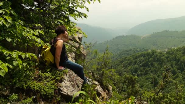 Vrouw wandelaar zittend op de klif in de bergen - Video