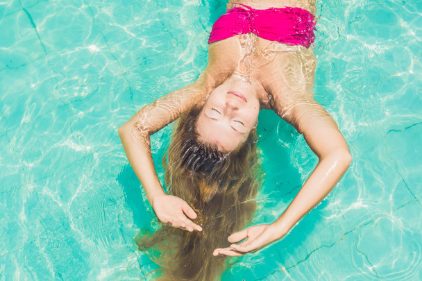 Beautiful young woman floating in pool  - Фото, зображення