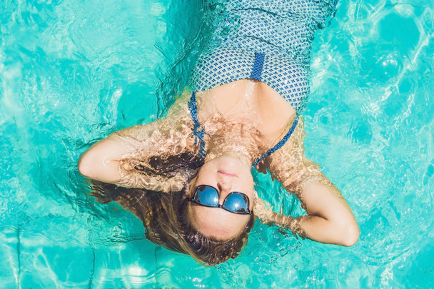 Beautiful young woman floating in pool  - Foto, afbeelding