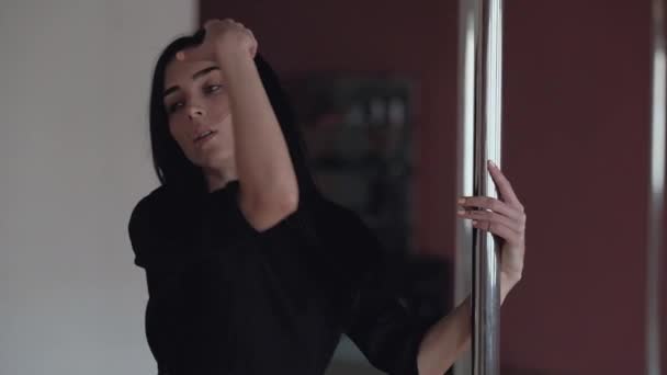 sexy junges Mädchen tanzt auf der Stange, mit langen schwarzen Haaren und schwarzer Kleidung - Filmmaterial, Video
