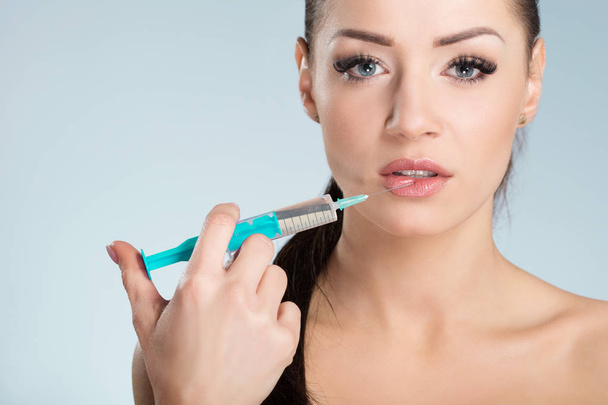 Beautiful young woman taking herself lips injection - Foto, immagini