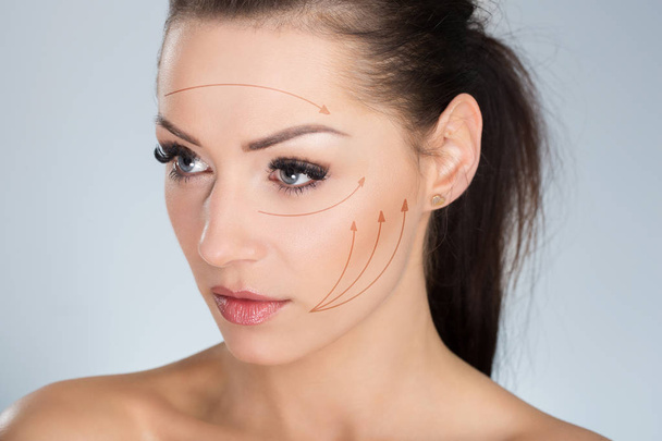 Young serious woman with surgical markers on face - Photo, image