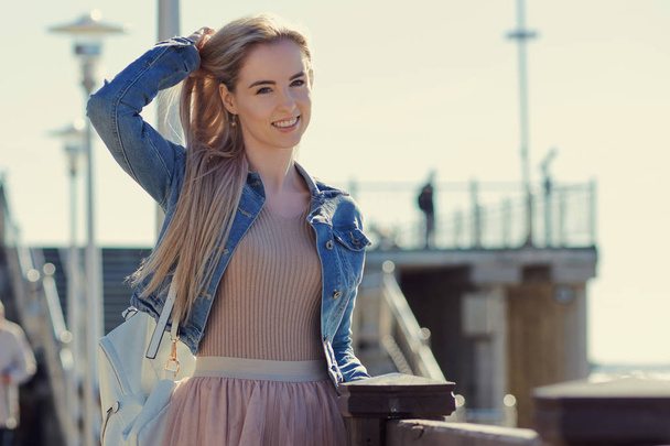 Young cheerful girl on the seashore. Young blonde woman smiling. Trendy style - Valokuva, kuva