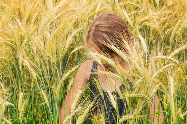 Meisje ondergedompeld onder de spikes van een rijping graan-veld - Foto, afbeelding